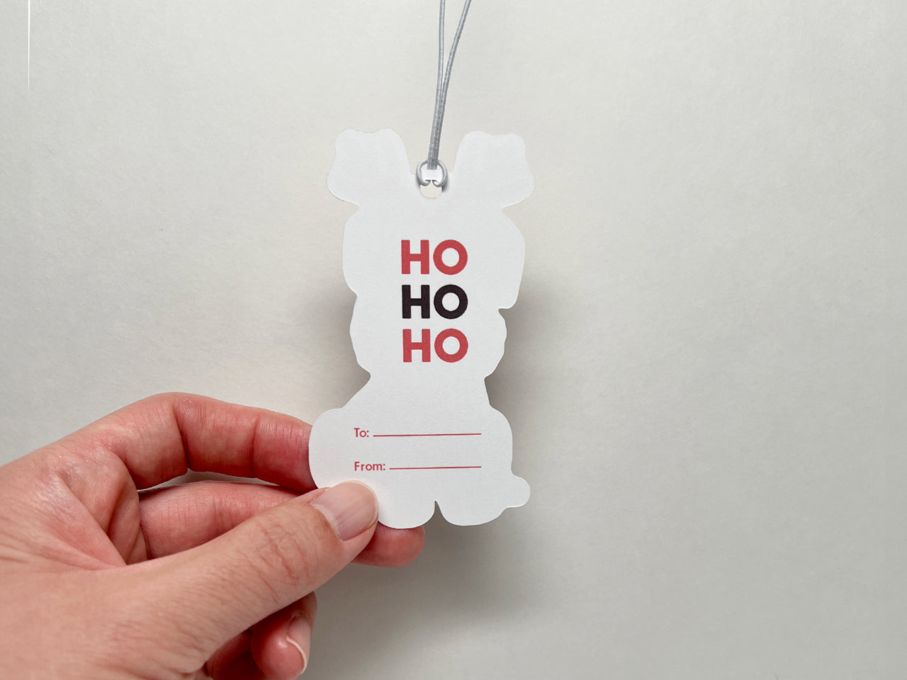 A close-up image of the back of a reindeer Schnauzer holiday gift tag. The tag features HO HO HO text in festive red and maroon and includes spaces for personalization. Perfect for to Christmas gift wrapping and dog-themed presents.