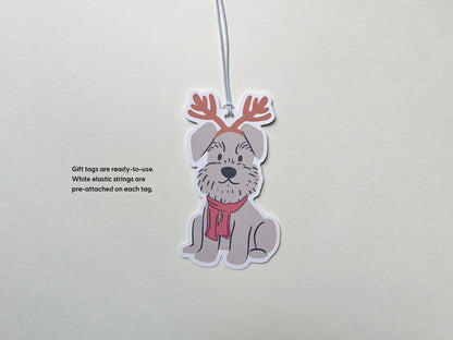 A reindeer Schnauzer holiday gift tag with a white elastic string pre-attached, ready to use. The handmade tag features a cute gray Schnauzer wearing reindeer antlers and a red scarf, perfect for Christmas gift wrapping and pet-themed holiday decor.