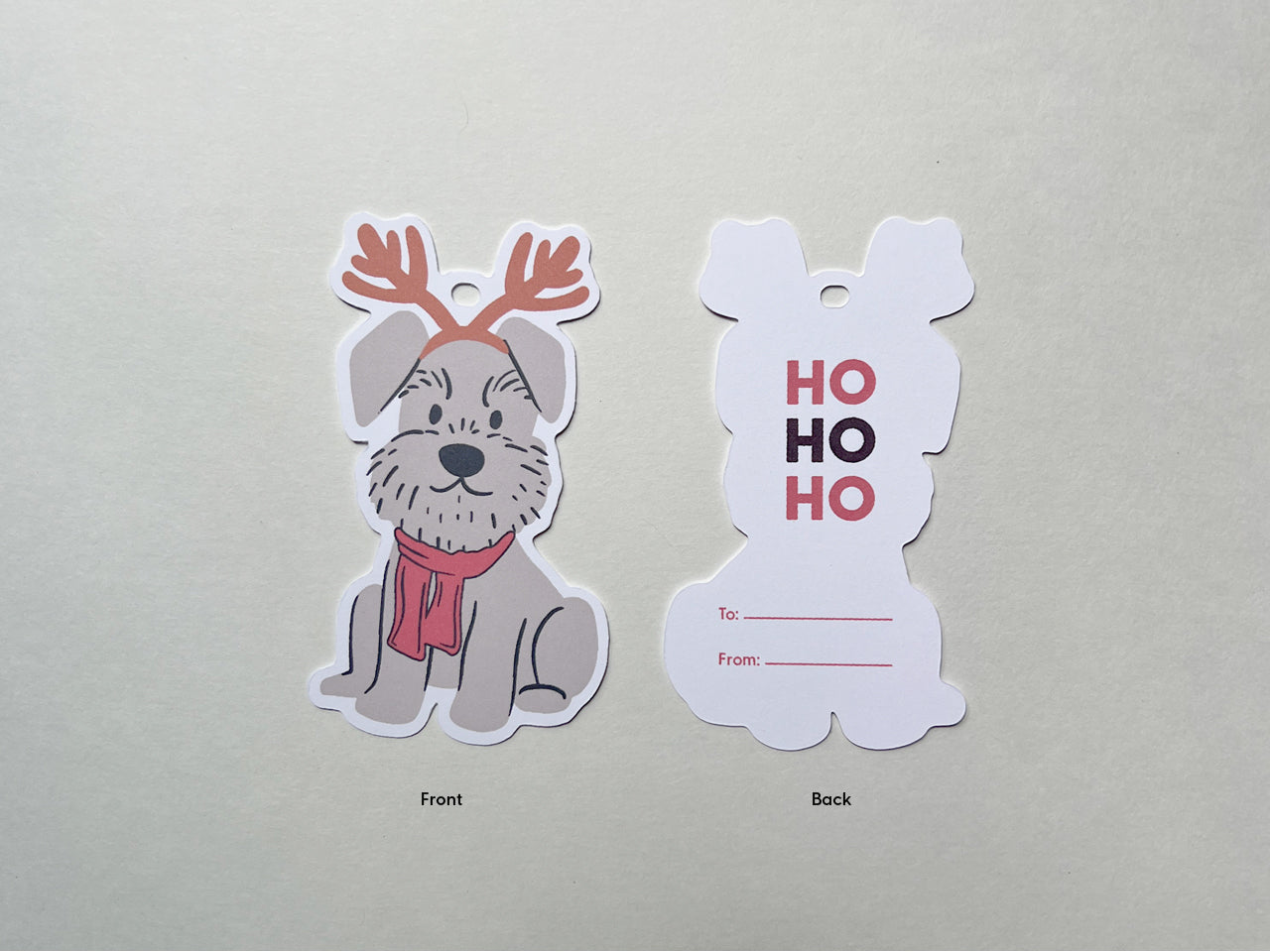 Front and back views of a reindeer Schnauzer holiday gift tag. The front features a festive gray Schnauzer with reindeer antlers and a red scarf, while the back displays HO HO HO text in red and maroon for name of recipient.