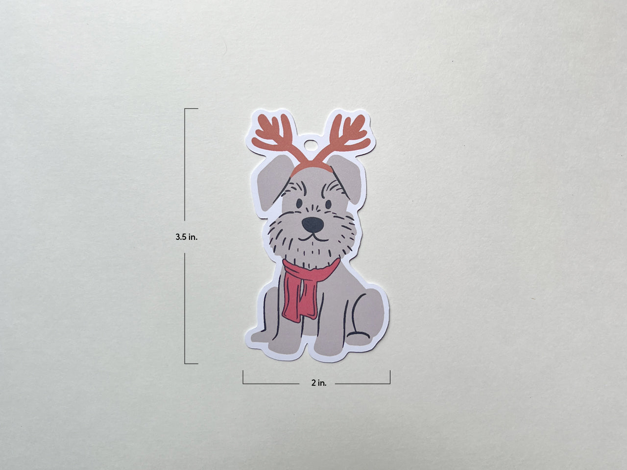 A reindeer Schnauzer holiday gift tag shown on a plain background with dimensions labeled: 3.5 inches tall and 2 inches wide. The tag features a cute Schnauzer dog with reindeer antlers and a red scarf, perfect for Christmas gift wrapping.