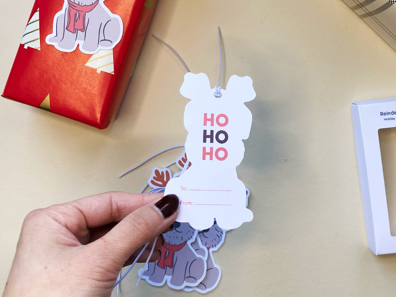 A close-up image of the back of a reindeer Schnauzer holiday gift tag. The tag features HO HO HO text in festive red and maroon and includes spaces for personalization. Perfect for to Christmas gift wrapping and dog-themed presents.