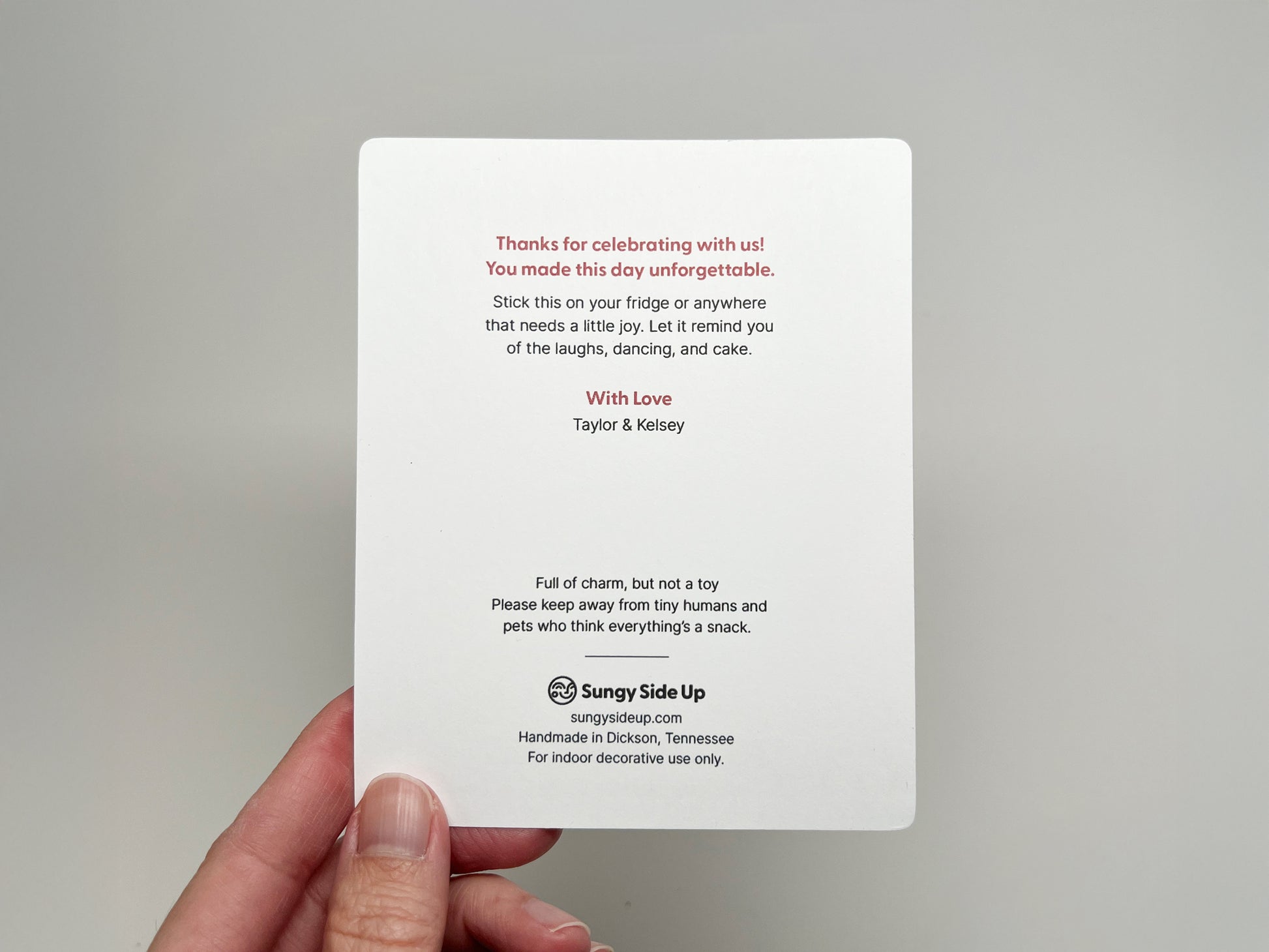 Back of a customizable wedding favor card featuring a thank-you note in red and black text. It thanks guests for celebrating, includes couple names, playful care instructions, and Sungy Side Up branding at the bottom.