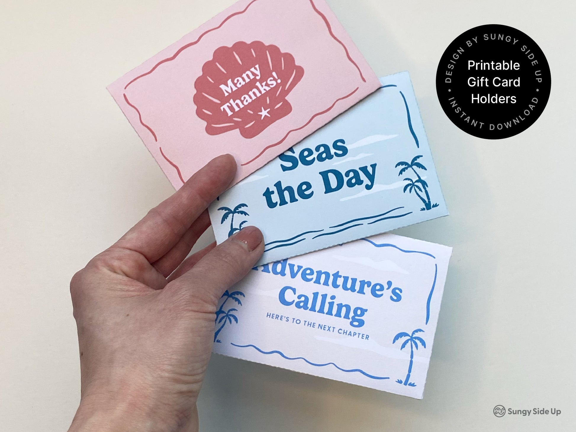 A hand holds three folded printable gift card holders in a fan arrangement, featuring retro beach-themed designs in pink, light blue, and white. The cards read "Many Thanks!," "Seas the Day," and "Adventure’s Calling," each decorated with coastal elements like seashells and palm trees. These digital gift card sleeves are part of an instant download bundle, perfect for thank you gifts, graduations, farewell parties, and summer-themed celebrations or events.