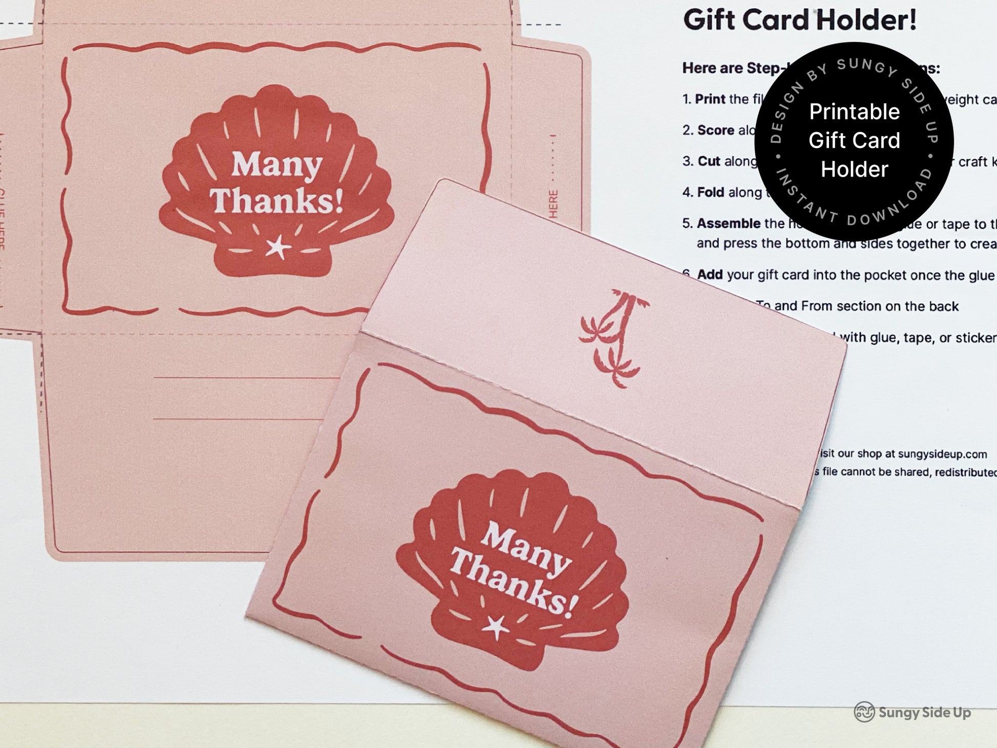 Flat lay showing a printable retro-style gift card holder in pink and red with a seashell design and scalloped edges. One holder is fully assembled and another is uncut on the printed template sheet. A step-by-step instruction page is partially visible in the background. The design is intended for 8.5" x 11" paper and is available as an instant download. Ideal for thank-you gifts, beach-themed events, or DIY stationery lovers looking for a unique and creative presentation.