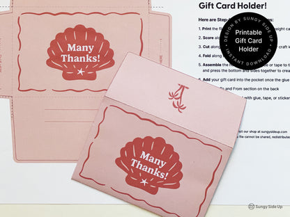 Flat lay showing a printable retro-style gift card holder in pink and red with a seashell design and scalloped edges. One holder is fully assembled and another is uncut on the printed template sheet. A step-by-step instruction page is partially visible in the background. The design is intended for 8.5" x 11" paper and is available as an instant download. Ideal for thank-you gifts, beach-themed events, or DIY stationery lovers looking for a unique and creative presentation.