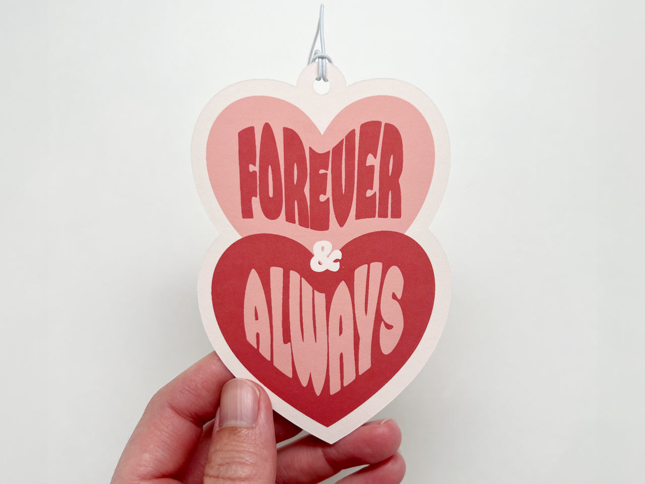 A close-up of a retro-style wedding gift tag featuring two stacked hearts. The top heart is pink with the word Forever in bold red retro typography, while the bottom heart is red with the word Always in pink.