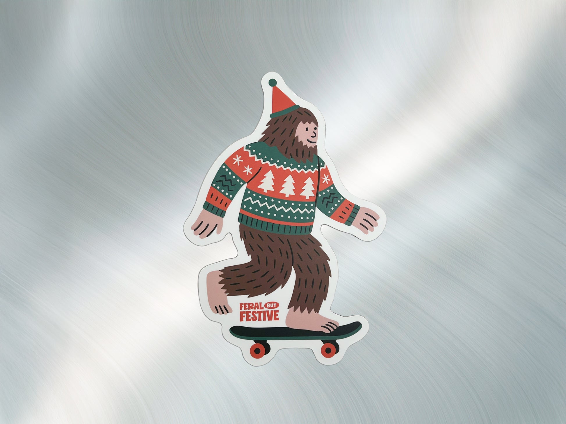 Festive Sasquatch skateboard magnet with holiday sweater and hat displayed on a brushed metal surface, handmade holiday magnet by Sungy Side Up.