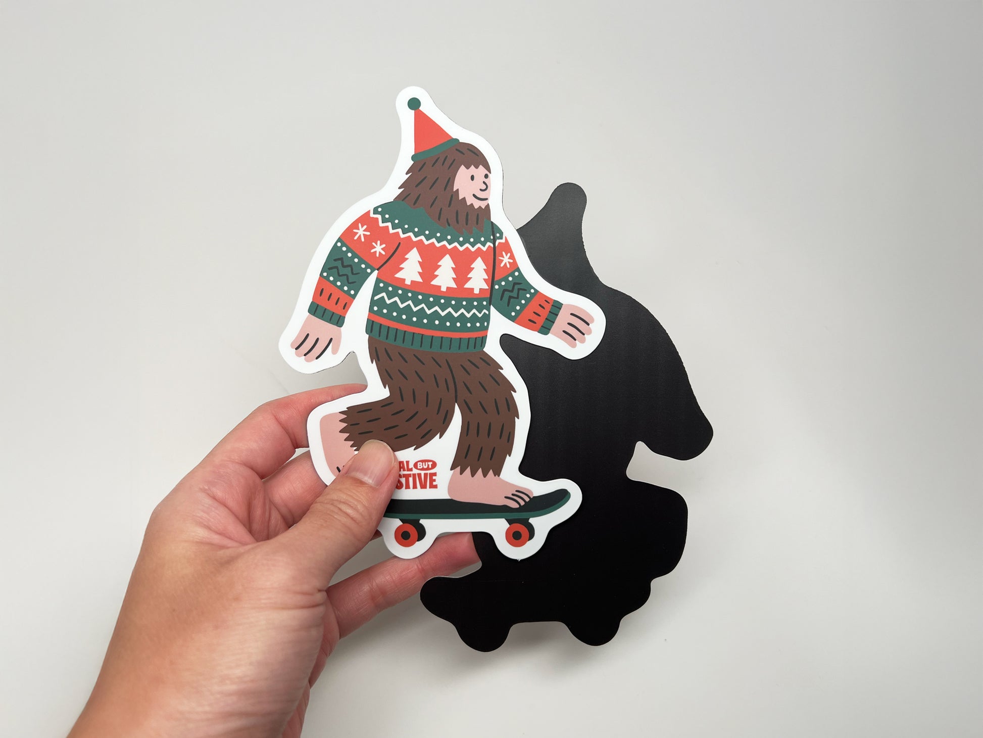 Holiday Bigfoot magnet front and black magnetic backing shown together, handmade festive Sasquatch fridge magnet by Sungy Side Up.