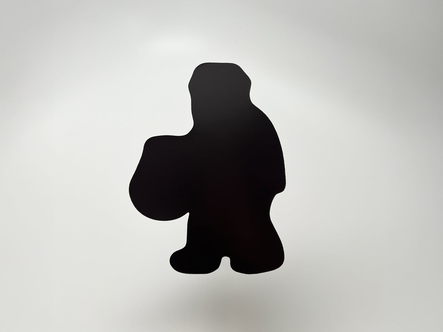 Back view of die-cut Halloween magnet shaped like a Sasquatch carrying a pumpkin bucket. Solid black magnetic surface designed to securely stick to fridges, lockers, and metal surfaces. Durable and lightweight Halloween décor, perfect for collectors of quirky cryptid and spooky magnets.
