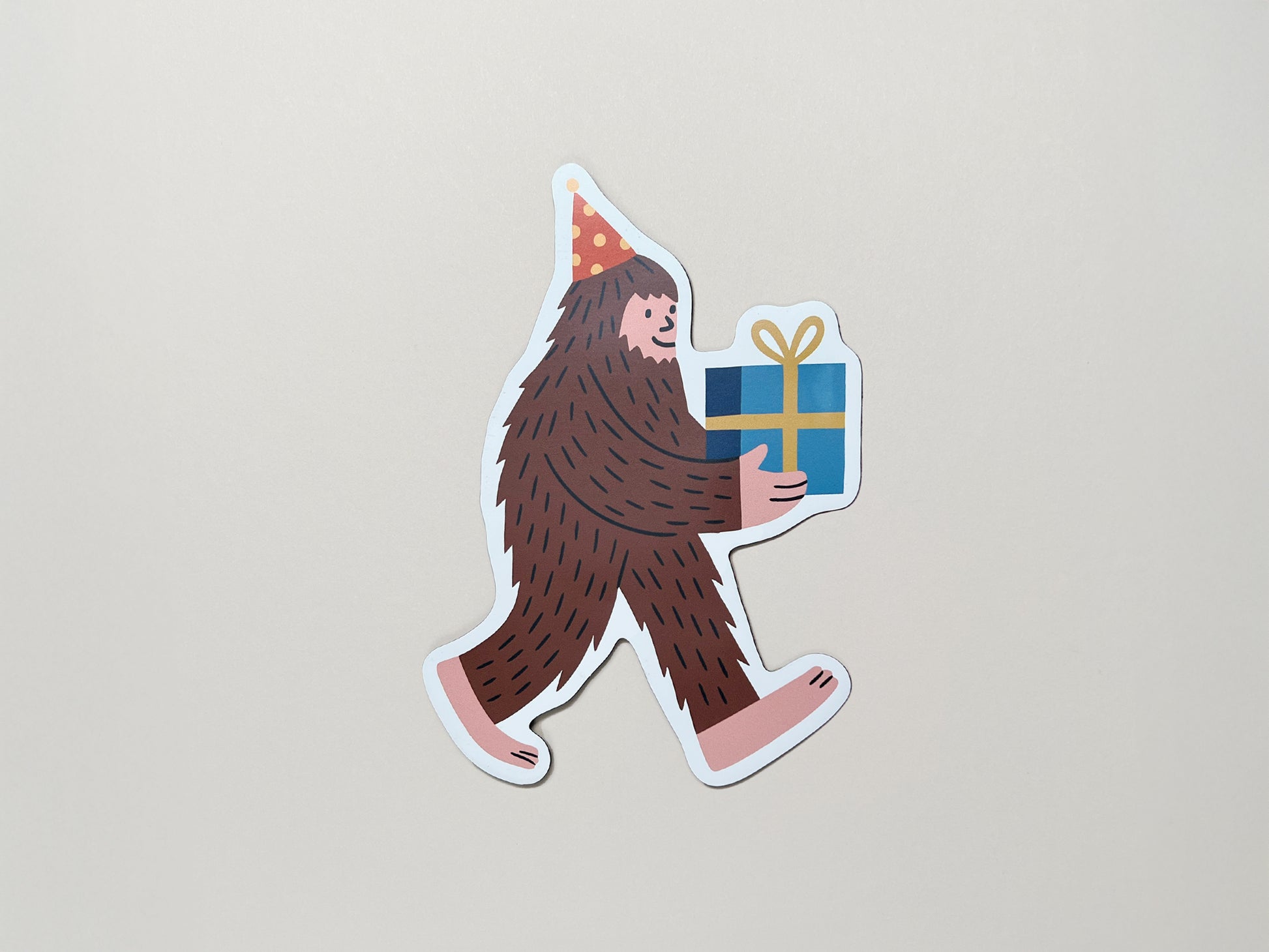 Funny sasquatch magnet with party hat and gift – quirky die-cut fridge magnet for birthdays, cryptid lovers, bigfoot fans, and offbeat celebration gifts.