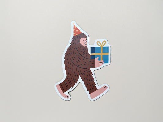 Funny sasquatch magnet with party hat and gift – quirky die-cut fridge magnet for birthdays, cryptid lovers, bigfoot fans, and offbeat celebration gifts.