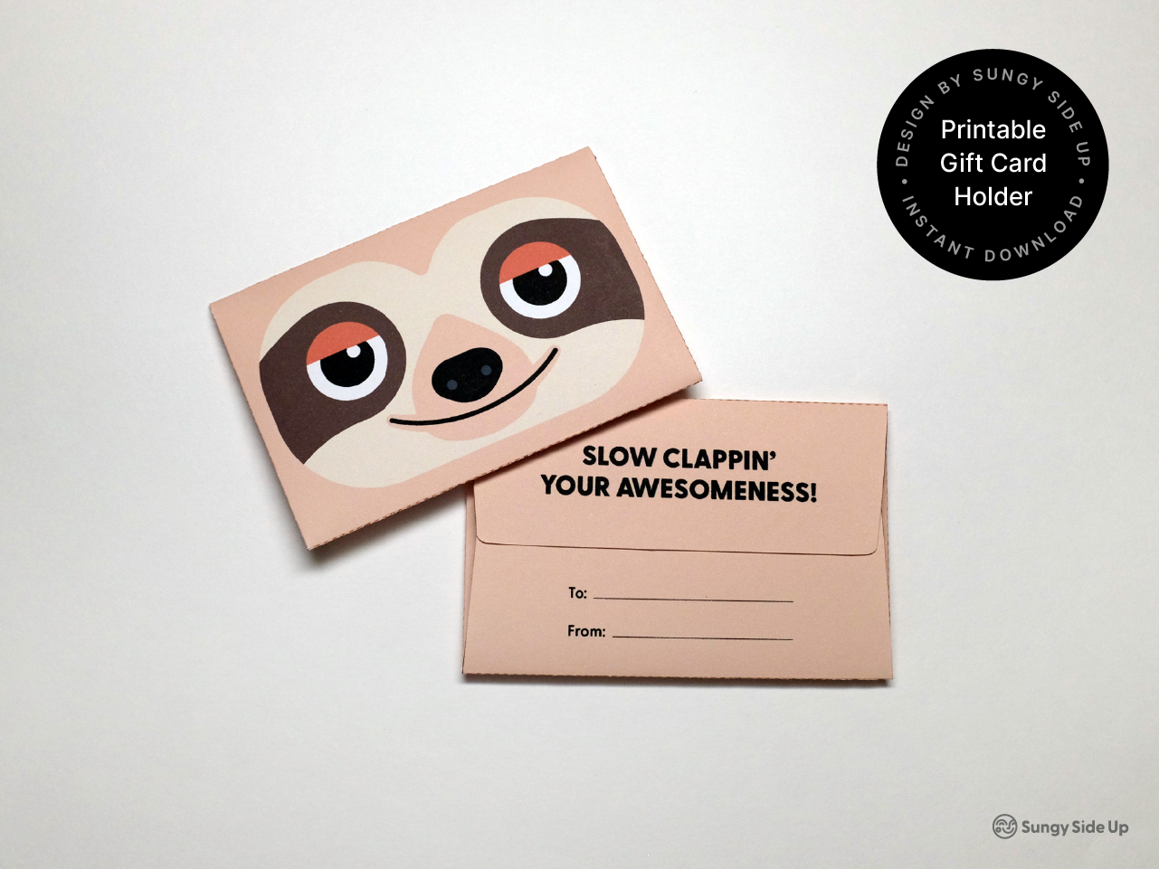 A printable sloth gift card holder design featuring a cartoon sloth face with large eyes and a brown and tan color palette. The back panel includes the phrase “Slow Clappin’ Your Awesomeness!” in bold text and space for “To” and “From” personalization. Displayed on a white background, this DIY craft is a unique, animal-themed option for gift-giving.