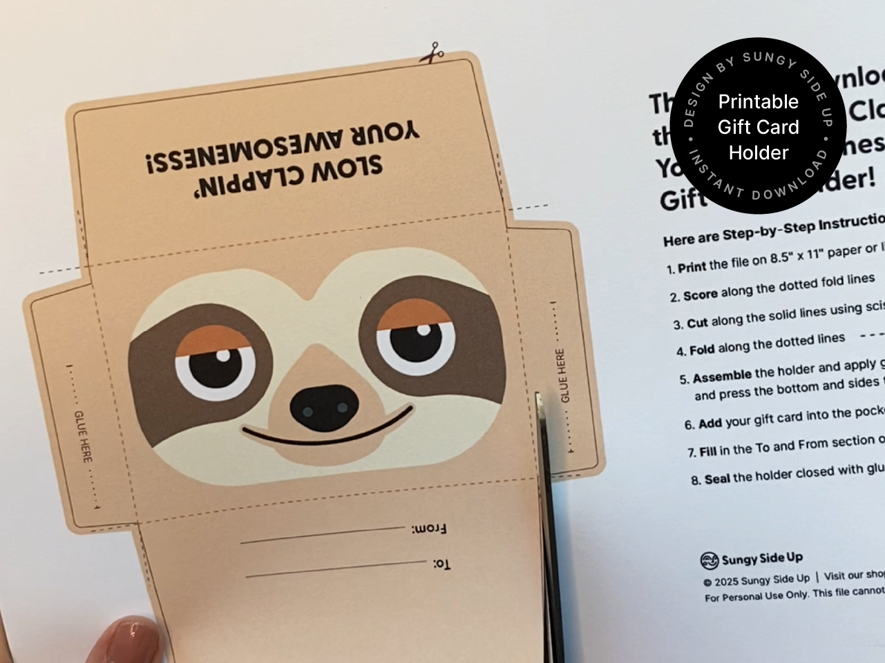 A close-up of the sloth gift card holder front panel showcasing the smiling cartoon sloth design in tan, cream, and brown tones with a slight orange accent on the eyes. The playful expression adds personality to the design, perfect for birthdays, thank-yous, and special occasions. The edges show precise cutting, and the cardstock texture is visible, emphasizing the handmade aspect of this printable project.