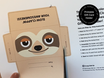 A close-up of the sloth gift card holder front panel showcasing the smiling cartoon sloth design in tan, cream, and brown tones with a slight orange accent on the eyes. The playful expression adds personality to the design, perfect for birthdays, thank-yous, and special occasions. The edges show precise cutting, and the cardstock texture is visible, emphasizing the handmade aspect of this printable project.