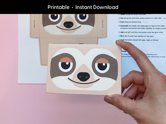 A hand holds a completed sloth gift card holder made from a printable template. The front features a smiling cartoon sloth with warm brown and beige tones. The background shows the flat printable sheet with cutting and folding guides. The image highlights the finished product’s size and quality, making it a great last-minute gift wrap option for kids, teachers, or anyone who loves animals and handmade gifting ideas.