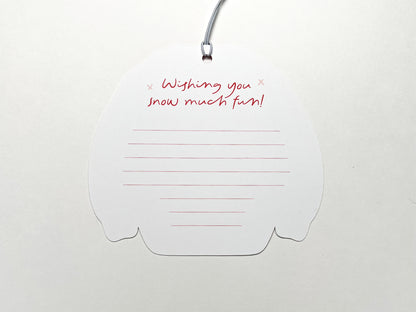 Back view of a Christmas sweater-shaped gift tag with a lined space for writing a personalized message. At the top, in festive red script, it says "Wishing you snow much fun!" with small snowflake accents. The tag is attached to a white string, ready to be used for holiday gift wrapping.