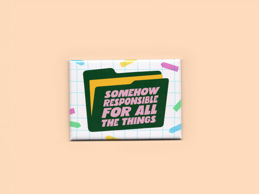 Rectangular magnet with a white grid background and colorful confetti accents. A dark green file folder graphic features pink text that reads “Somehow Responsible for All the Things.” The magnet is displayed against a beige background.