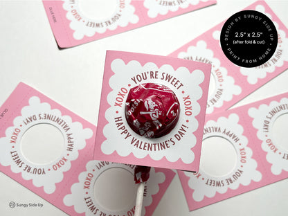 Assembled Valentines Day lollipop holder featuring a pink scalloped design holding a red lollipop. Surrounded by additional printable lollipop holders for crafting and decorating Valentines Day gifts. Ideal for classroom exchanges and party favors.