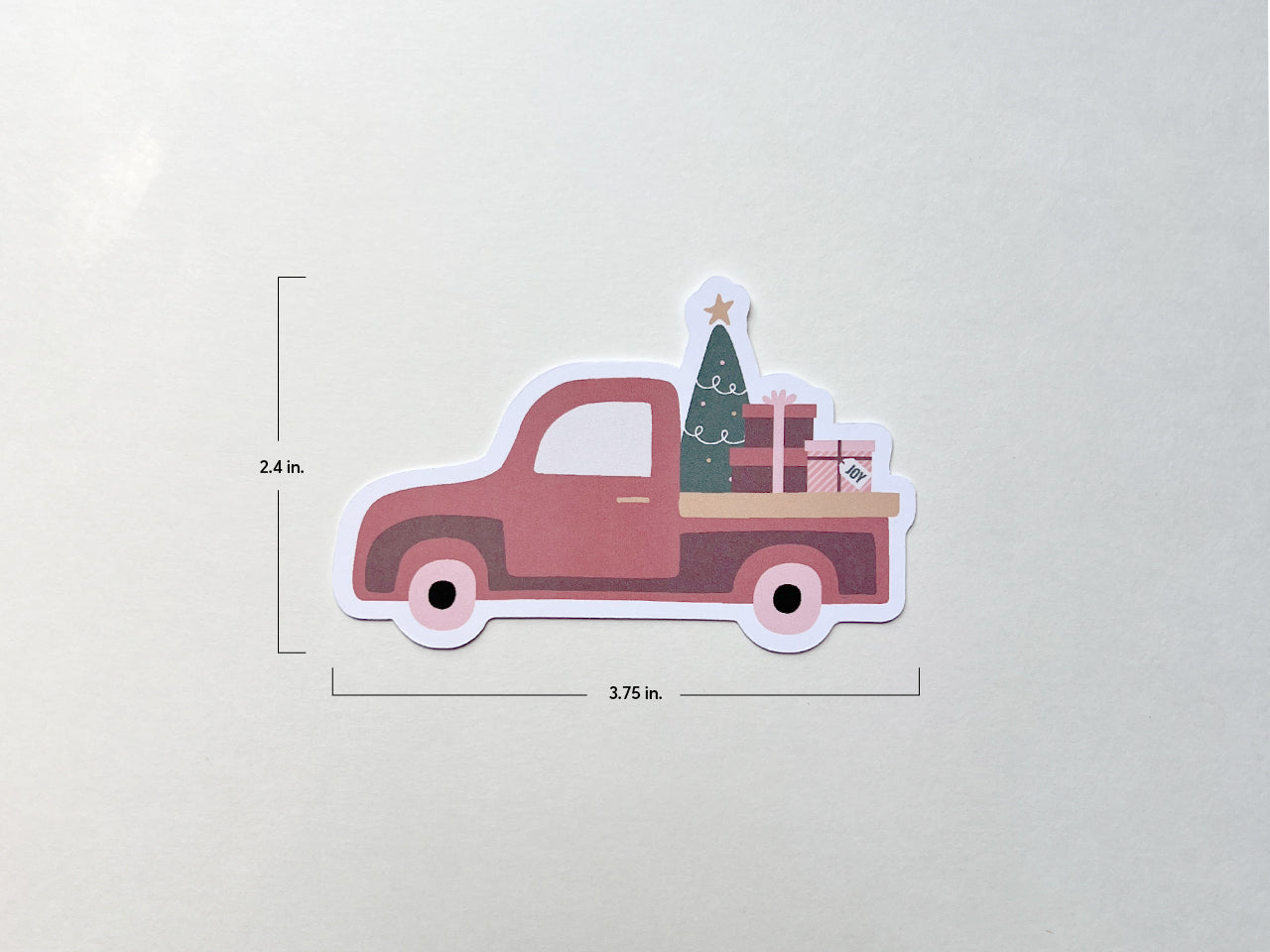 A burnt orange vintage style Christmas truck die-cut note card with dimensions displayed: 3.75 inches wide and 2.4 inches tall. The truck features a Christmas tree with a star and stacked gift boxes in the truck bed, set against a plain background.