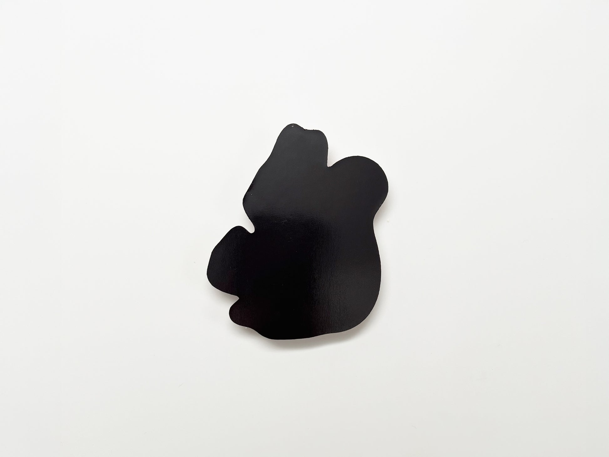Back view of a handmade die-cut fridge magnet shaped like a squirrel, showing the smooth black magnetic surface designed to securely attach to refrigerators, lockers, or other magnetic surfaces.