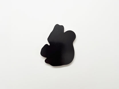Back view of a handmade die-cut fridge magnet shaped like a squirrel, showing the smooth black magnetic surface designed to securely attach to refrigerators, lockers, or other magnetic surfaces.