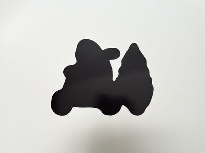 Back view of a handmade die-cut magnet shaped like a yeti riding a scooter and pulling a Christmas tree. The magnet side is solid black with a glossy finish, cut precisely to match the front design, showing durability and strong hold for use on fridges, lockers, or other magnetic surfaces.
