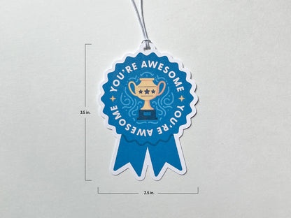 A blue ribbon-shaped gift tag with the words You're Awesome surrounding a golden trophy illustration. The gift tag measures 3.5 inches in height and 2.5 inches in width. A white string is attached at the top for easy hanging.